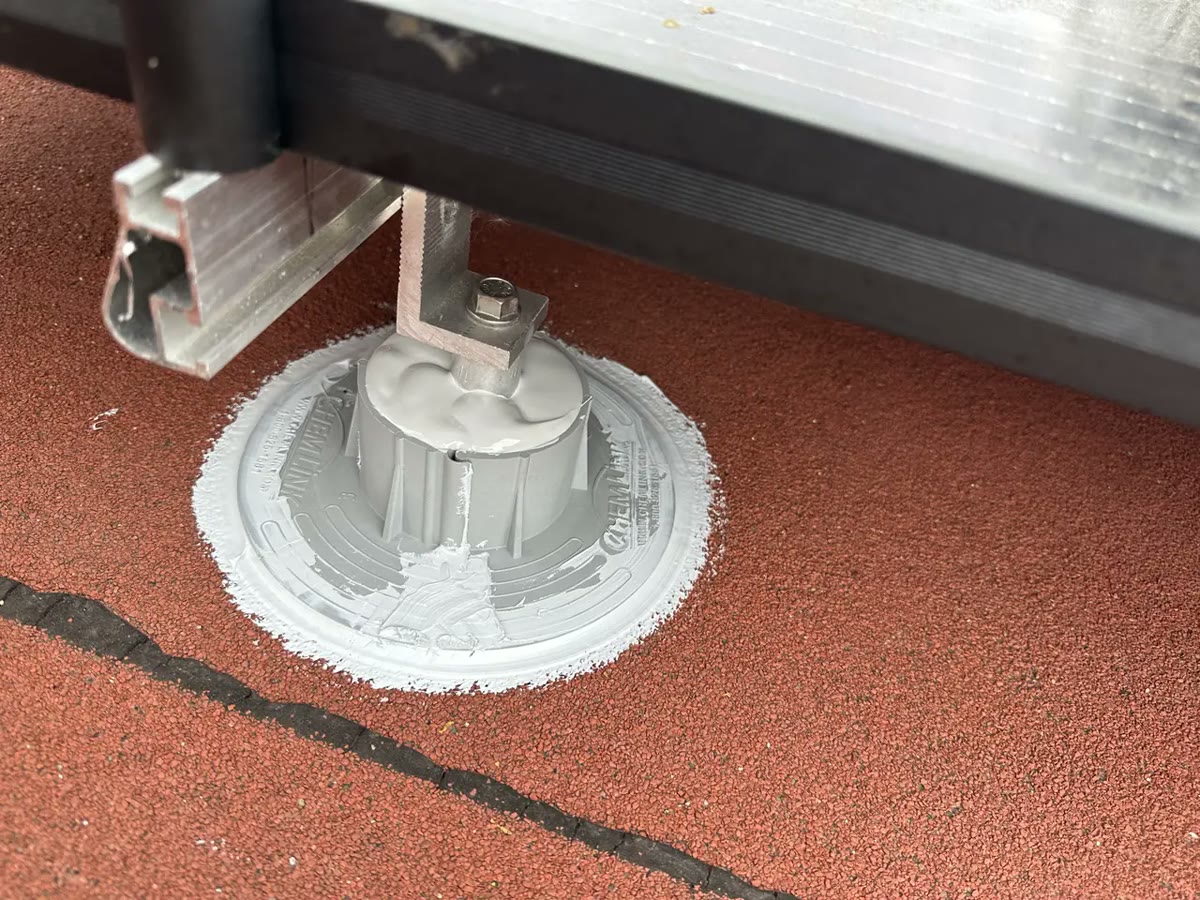 Close-up of a mount base sealed to the roof covering, with the rail bracket above it