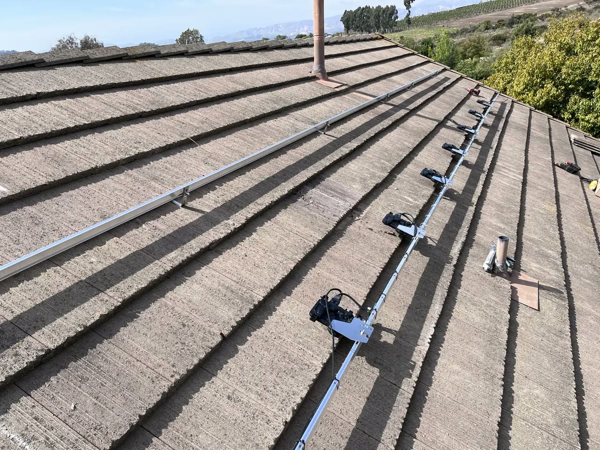 Mounting rails running across a composition shingle roof during installation