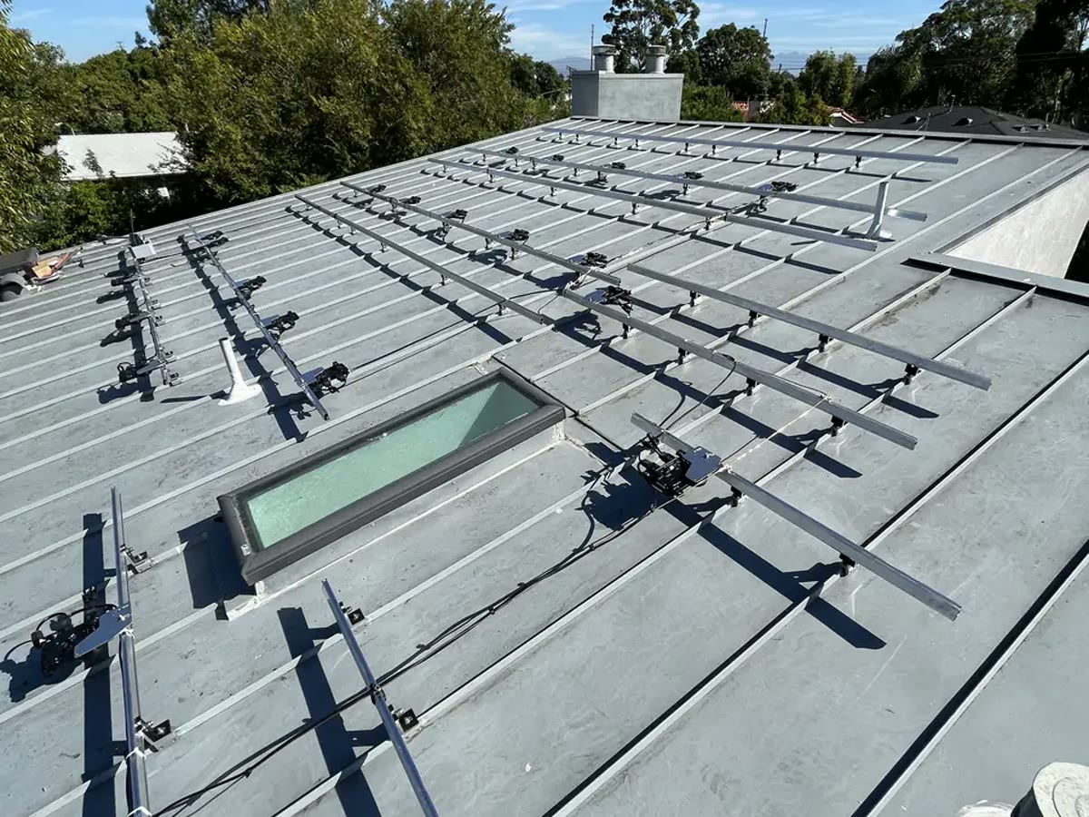 Mounting rails clamped to the raised seams of a standing-seam metal roof